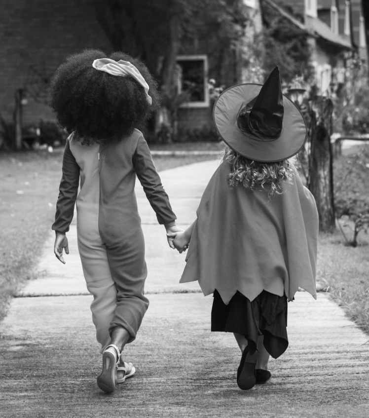 grayscale photography of two children holding hands together